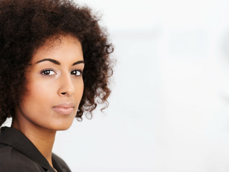 Headshot of an african-american women standing to the left, serious and pensive.