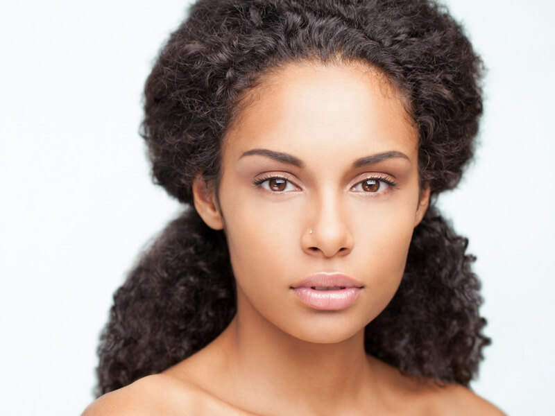 Headshot of African-American women looking serious, without a shirt. Thinking about risks of uterine fibroids.