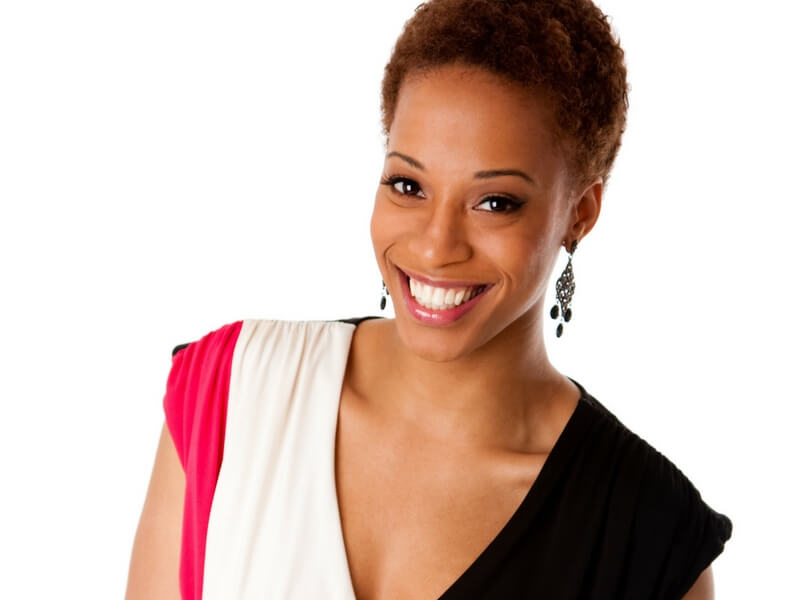 An African-American woman with short hair, dressed-up and smiling, living a happy life after treating fibroids.