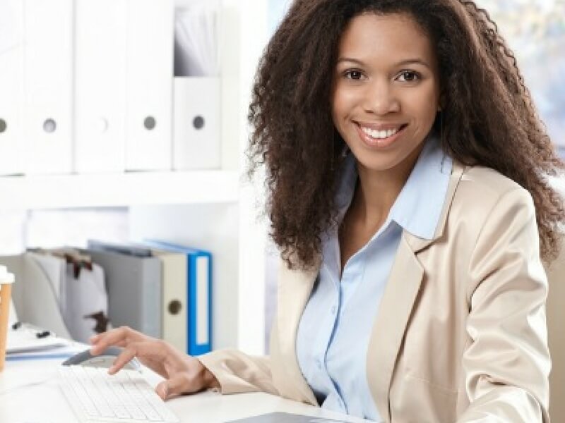 A business women typing at her desk, happy after getting UFE fibroid treatment.