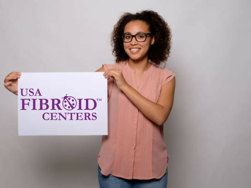 Happy woman holding a USA Fibroid Centers sign. 