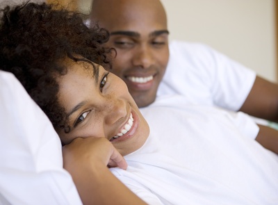 Young, happy couple lying on bed smiling, portrait of woman, close-up
