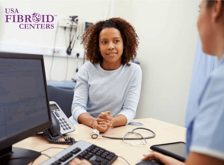 A woman sitting at a doctor's desk talking about uterine fibroids. 