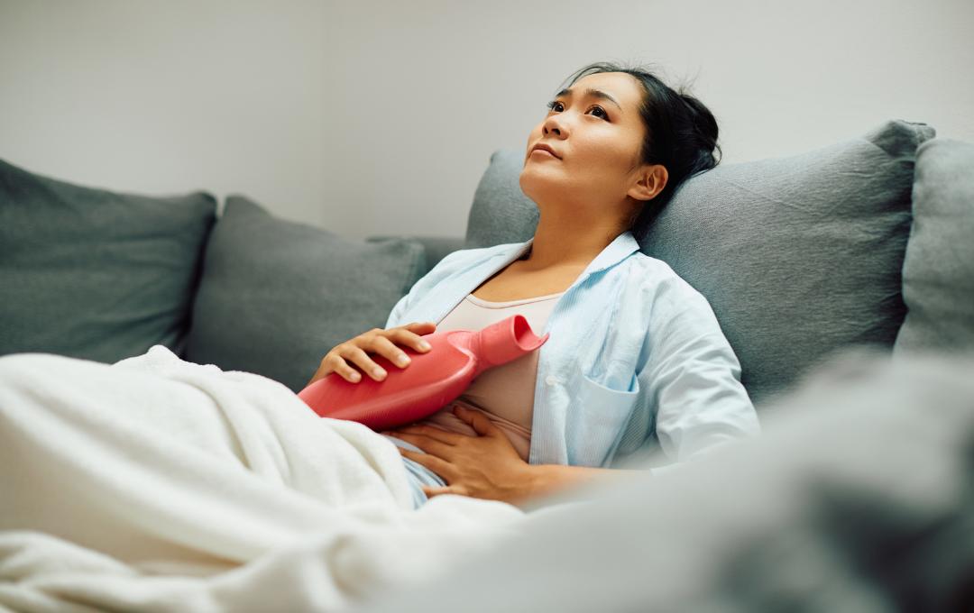 Common Questions About The Detection Of Fibroids 5 Woman laying down with hot water bottle to relieve abdominal pain.